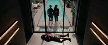 Movie still from “Margaux” (2022), directed by Steven C. Miller – Two people standing by a swimming pool looking at a man laying on the ground; Wide shot, Overhead angle