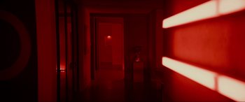 Movie still from “Margaux” (2022), directed by Steven C. Miller – A hallway with a red light shining on the wall; Wide shot, High angle