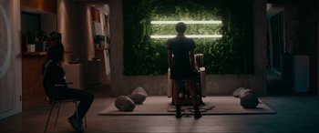 Movie still from “Margaux” (2022), directed by Steven C. Miller – A woman standing in front of a window with plants; Wide shot, Low angle