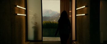 Movie still from “Margaux” (2022), directed by Steven C. Miller – A woman standing in front of an open door looking out at the mountains; Extreme Wide shot, Low angle