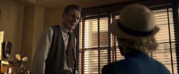 Movie still from “Marlowe” (2022), directed by Neil Jordan – A man wearing a vest and a tie standing in front of another man wearing a hat; Medium shot, Over the shoulder angle