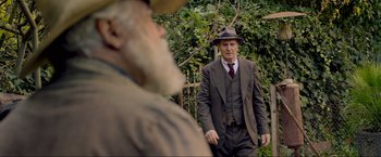 Movie still from “Marlowe” (2022), directed by Neil Jordan – A man in a suit and hat standing next to a man with a beard; Medium shot, Over the shoulder angle