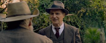 Movie still from “Marlowe” (2022), directed by Neil Jordan – An older man wearing a suit and a hat; Close Up shot, Over the shoulder angle