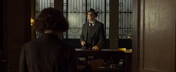 Movie still from “Marlowe” (2022), directed by Neil Jordan – A man in a suit and hat standing in front of a mirror; Medium shot, Over the shoulder angle