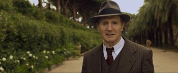 Movie still from “Marlowe” (2022), directed by Neil Jordan – An older man wearing a suit and a hat; Close Up shot, Over the shoulder angle