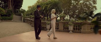 Movie still from “Marlowe” (2022), directed by Neil Jordan – A man and a woman are walking in a park; Wide shot, Low angle