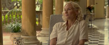 Movie still from “Marlowe” (2022), directed by Neil Jordan – A woman sitting in a chair in front of pillars; Close Up shot, Over the shoulder angle
