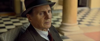 Movie still from “Marlowe” (2022), directed by Neil Jordan – An older man wearing a hat and a suit; Close Up shot, Over the shoulder angle