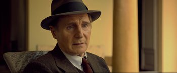 Movie still from “Marlowe” (2022), directed by Neil Jordan – An older man wearing a suit and a hat; Close Up shot, Over the shoulder angle