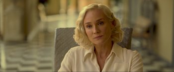 Movie still from “Marlowe” (2022), directed by Neil Jordan – A woman with blonde hair sitting in a chair looking at the camera; Close Up shot, Over the shoulder angle