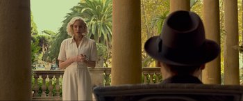 Movie still from “Marlowe” (2022), directed by Neil Jordan – An older woman in a white dress talking to an older man in a hat; Medium shot, Over the shoulder angle