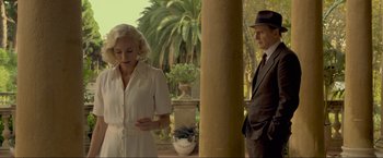 Movie still from “Marlowe” (2022), directed by Neil Jordan – A man and a woman standing next to each other in front of palm trees; Medium shot, Over the shoulder angle