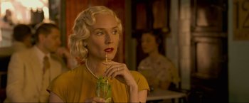 Movie still from “Marlowe” (2022), directed by Neil Jordan – A woman drinking a drink with a straw in her hand; Close Up shot, Over the shoulder angle