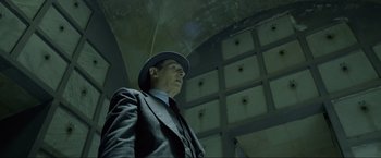 Movie still from “Marlowe” (2022), directed by Neil Jordan – A man in a suit and hat standing in a room; Medium shot, Low angle