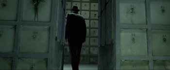 Movie still from “Marlowe” (2022), directed by Neil Jordan – A man in a suit and hat walking down a hall way; Wide shot, Low angle