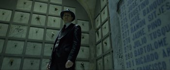 Movie still from “Marlowe” (2022), directed by Neil Jordan – A man in a suit and hat standing in front of a wall; Medium shot, Low angle