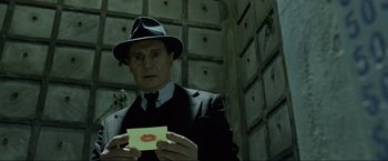 Movie still from “Marlowe” (2022), directed by Neil Jordan – A man in a suit and hat holding a piece of paper; Close Up shot, Low angle