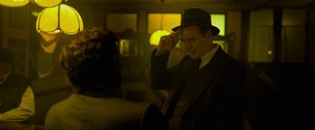 Movie still from “Marlowe” (2022), directed by Neil Jordan – A man wearing a hat and a suit and tie; Medium shot, Over the shoulder angle