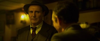 Movie still from “Marlowe” (2022), directed by Neil Jordan – An older man wearing a suit and a hat looking at himself in the mirror; Close Up shot, Over the shoulder angle