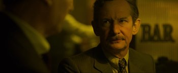 Movie still from “Marlowe” (2022), directed by Neil Jordan – An older man wearing a suit and a tie; Close Up shot, Over the shoulder angle