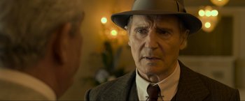Movie still from “Marlowe” (2022), directed by Neil Jordan – An older man wearing a suit and a hat; Close Up shot, Over the shoulder angle
