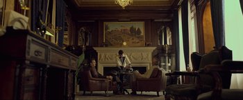 Movie still from “Marlowe” (2022), directed by Neil Jordan – Three men sitting in a living room next to a fireplace; Wide shot, Low angle