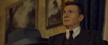 Movie still from “Marlowe” (2022), directed by Neil Jordan – A man wearing a suit and tie looking up; Close Up shot, Over the shoulder angle