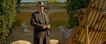 Movie still from “Marlowe” (2022), directed by Neil Jordan – An older man in a suit and hat standing in front of a woman; Medium shot, Over the shoulder angle
