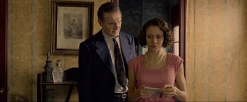 Movie still from “Marlowe” (2022), directed by Neil Jordan – An older man standing next to a young woman; Medium shot, Over the shoulder angle