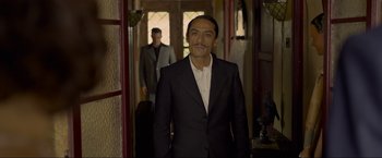 Movie still from “Marlowe” (2022), directed by Neil Jordan – A man in a suit standing in front of another man; Medium shot, Over the shoulder angle