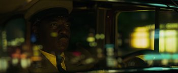 Movie still from “Marlowe” (2022), directed by Neil Jordan – A man wearing a hat sitting in a car; Close Up shot, Low angle