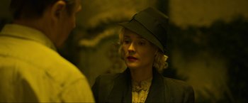 Movie still from “Marlowe” (2022), directed by Neil Jordan – A woman wearing a black hat and a white dress; Close Up shot, Over the shoulder angle