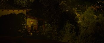 Movie still from “Marlowe” (2022), directed by Neil Jordan – A man standing in front of a house at night; Extreme Wide shot, Low angle
