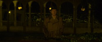Movie still from “Marlowe” (2022), directed by Neil Jordan – A man in a raincoat and hat standing in the rain at night; Medium shot, Low angle