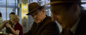 Movie still from “Marlowe” (2022), directed by Neil Jordan – A man in a suit and a hat; Close Up shot, Over the shoulder angle
