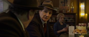 Movie still from “Marlowe” (2022), directed by Neil Jordan – An older man wearing a hat sitting next to another man; Close Up shot, Over the shoulder angle