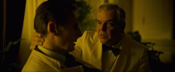 Movie still from “Marlowe” (2022), directed by Neil Jordan – A man in a suit and tie talking to another man in a suit and tie; Close Up shot, Over the shoulder angle
