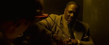 Movie still from “Marlowe” (2022), directed by Neil Jordan – A man in a suit and tie holding a pair of handcuffs; Close Up shot, High angle