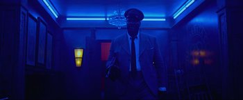 Movie still from “Marlowe” (2022), directed by Neil Jordan – A man in a suit and tie holding something in his hand; Medium shot, Low angle