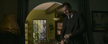Movie still from “Marlowe” (2022), directed by Neil Jordan – A man in a suit and tie holding a coffee pot; Medium shot, Low angle