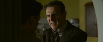 Movie still from “Marlowe” (2022), directed by Neil Jordan – An older man in a suit and tie talking to a younger man; Close Up shot, Over the shoulder angle