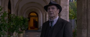 Movie still from “Marlowe” (2022), directed by Neil Jordan – An older man wearing a hat and a suit; Medium shot, Over the shoulder angle