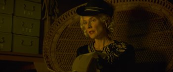 Movie still from “Marlowe” (2022), directed by Neil Jordan – An older woman wearing a hat and holding an umbrella; Close Up shot, Low angle