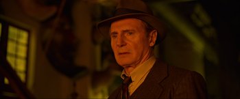 Movie still from “Marlowe” (2022), directed by Neil Jordan – An older man wearing a hat and a suit; Close Up shot, Over the shoulder angle