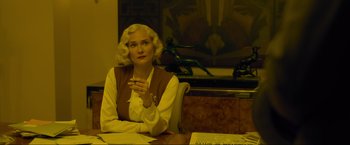 Movie still from “Marlowe” (2022), directed by Neil Jordan – A woman sitting at a table with a cigarette in her mouth; Medium shot, Low angle