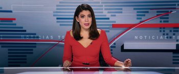 Movie still from “Marry Me” (2022), directed by Kat Coiro – A woman in a red dress sitting at a desk; Medium shot, Low angle