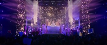 Movie still from “Marry Me” (2022), directed by Kat Coiro – A group of people standing in front of a stage; Extreme Wide shot, High angle