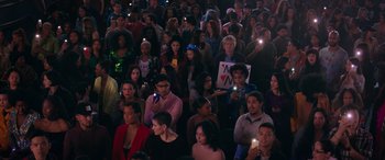 Movie still from “Marry Me” (2022), directed by Kat Coiro – A crowd of people sitting and standing in a dark room; Extreme Wide shot, High angle