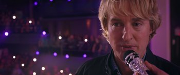 Movie still from “Marry Me” (2022), directed by Kat Coiro – A person with a microphone; Close Up shot, Low angle