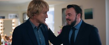 Movie still from “Marry Me” (2022), directed by Kat Coiro – Two men in business suits , one of whom has his hand on the shoulder of another man; Close Up shot, Over the shoulder angle